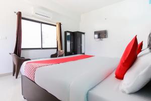 - un lit blanc avec des oreillers rouges dans l'établissement OYO Flagship 49907 Hotel Udaipur Valley, à Udaipur