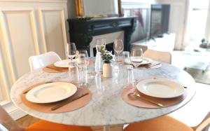 einen Esstisch mit Tellern und Gläsern darauf in der Unterkunft Le Carré Bleu - Studio Confort - Centre-ville in Dieppe