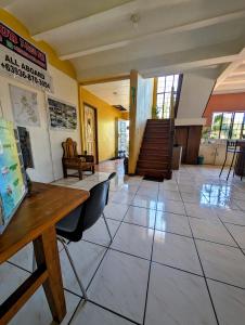 un vestíbulo con mesa, sillas y escaleras en Screaming Gecko Hostel Air-Con, en Busuanga