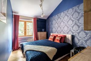 a bedroom with blue walls and a bed with red pillows at Golden Villa Saska Kępa in Warsaw