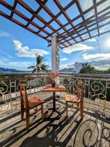 een patio met een tafel en stoelen op een balkon bij Screaming Gecko Hostel Air-Con in Busuanga