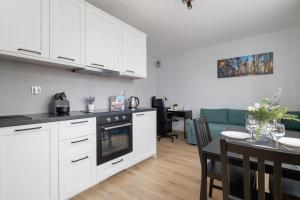 a kitchen and dining room with white cabinets and a table at Luxury Apartment with Balcony & Parking Cracow by Renters Prestige in Krakow