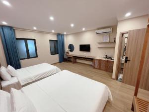 a hotel room with two beds and a flat screen tv at Mai An Homestays in Móng Cái