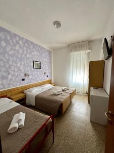 una camera d'albergo con due letti e una finestra di Hotel Enna Rimini a Rimini