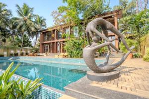 uma estátua de duas cobras ao lado de uma piscina em Elivaas Glass Villa Ultra Luxe 4BHK with Pvt Pool in Aldona em Goa