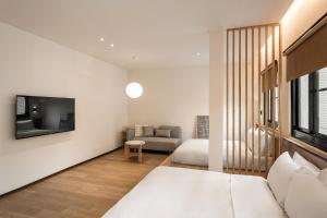 Habitación blanca con cama y sofá en 河映宿沐 River Trees Hotel, en Kaohsiung