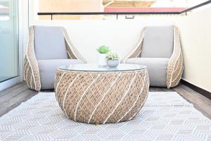 a living room with a rattan coffee table and two chairs at 3BR Penthouse at Hilton Beach by HolyGuest in Tel Aviv