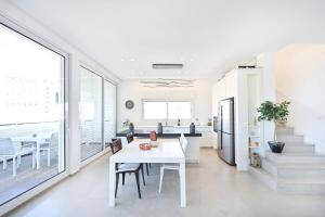 a white dining room with a white table and chairs at 3BR Penthouse at Hilton Beach by HolyGuest in Tel Aviv