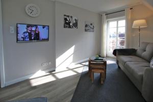 uma sala de estar com um sofá e uma televisão na parede em Starklef 29_ Whg_ 2 em Wyk auf Föhr