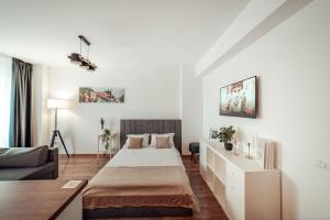 a white bedroom with a bed and a couch at Luxury Collection Studios at Q Residence Palas Mall in Iaşi