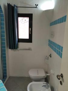 a bathroom with a white toilet and a window at NRH Baja Sardinia Cottage in Baja Sardinia