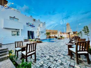 um pátio com cadeiras, uma mesa e uma piscina em Dolphina hotel & Restaurant em Dahab