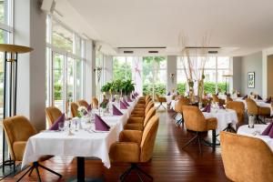 ein Esszimmer mit weißen Tischen, Stühlen und Fenstern in der Unterkunft Grand Hotel Binz in Binz