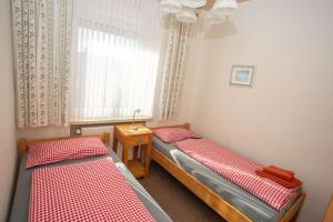 2 Betten in einem kleinen Zimmer mit Fenster in der Unterkunft Haus Ufen - In den Dünen 18c in Norderney