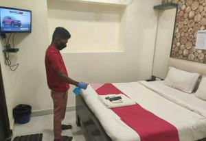 a man is making a bed in a room at OYO Hotel Sonali in Nagpur