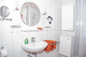 ein weißes Badezimmer mit einem Waschbecken und einem Spiegel in der Unterkunft Haus Ufen - In den Dünen 18c in Norderney