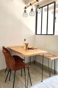 une table en bois avec deux chaises et deux fenêtres dans l'établissement Villa Maya - 4 Amellau - AVIGNON - CLIM - WIFI, à Avignon