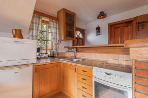 una cucina con armadietti in legno ed elettrodomestici bianchi di Vineyard Cottage Rataj 1 Hot Tub - Happy Rentals a Novo Mesto