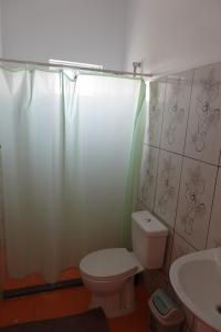 y baño con aseo, lavamanos y cortina de ducha. en Residencial Ribeira Torta, en Porto Novo