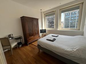 una camera con un letto e un comò e due finestre di Vittore Rooms & Apartment a Milano