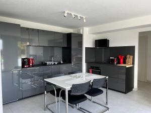 a kitchen with black cabinets and a white table and chairs at Oasis tout confort à Bergheim, Alsace in Bergheim