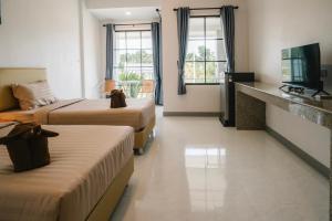 um quarto de hotel com duas camas e uma televisão em Chor Grande Resort em Trat