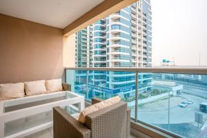 a balcony with a couch and chairs and a large window at Deluxe 2BR Apartment Dubai Marina View in Dubai