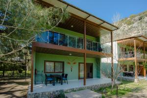 a green house with a table and chairs at Keyif Pension & Aparts in Cıralı