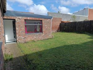 a brick house with a window and a yard at La Fretinoise in Fretin