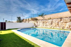 einen Pool in einem Garten neben einer Steinmauer in der Unterkunft beautiful villa private pool & Jacuzzi with panoramic views in Mutxamel