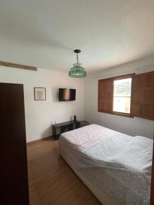 a bedroom with a bed and a television on the wall at Chácara Monte das Oliveiras in Marechal Floriano