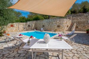 a patio with a table and a swimming pool at Dive into Summer - Kirki's Cozy Pool Gem on Paxoi in Ieromónachos