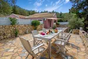 a patio with a table and chairs in a yard at Dive into Summer - Kirki's Cozy Pool Gem on Paxoi in Ieromónachos