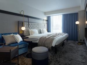 札幌市にある三井ガーデンホテル札幌ウエストの大きなベッドとソファが備わるホテルルームです。
