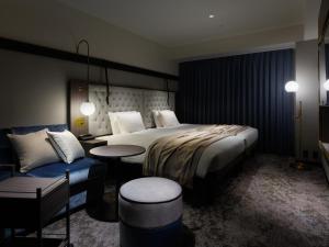 札幌市にある三井ガーデンホテル札幌ウエストのベッド、テーブル、椅子が備わるホテルルームです。