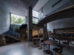 a restaurant with tables and chairs and a staircase at Neobridge Hotel in Shanghai