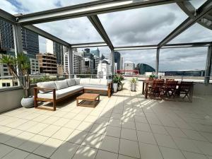 a patio with a couch and tables on a building at Cozy 2 Bedroom Apartment Darling Harbour in Sydney