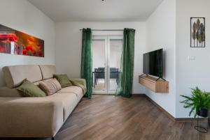 sala de estar con sofá y TV en Green Nest, ground floor apt with garden & garage, en Medulin