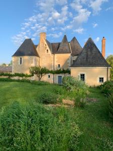 una casa vieja con un campo de hierba delante de ella en Belle Chambre et petit déjeuner au Manoir de la Faverie, en Beaumont-Pied-de-Boeuf