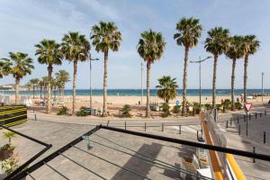 a view of a beach with palm trees and the ocean at Arsenal 31 by Seaward Suites in Villajoyosa