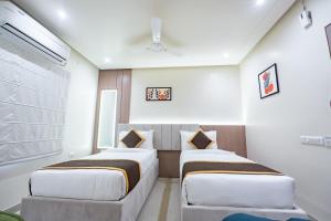 two beds in a room with white walls at DEV RESIDENCY ( A UNIT OF THE ELEGANCE ) in Varanasi