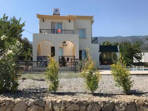 a large white house with bushes in front of it at Villa Alsancak Girne in Karavas