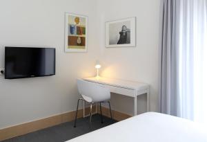 a room with a desk and a tv and a bed at Hotel Convento do Salvador in Lisbon