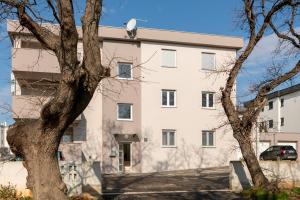 un edificio blanco con un árbol delante en Green Nest, ground floor apt with garden & garage, en Medulin