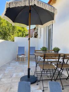 een tafel en stoelen onder een parasol op een patio bij Villa Maya - 3 Groussan - Avignon - CLIM - TERRASSE in Avignon