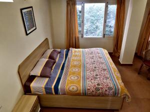 uma cama com uma colcha num quarto em Beechwood Holiday Apartments em Mussoorie