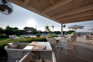 eine Terrasse mit Tischen, Stühlen und einem Sonnenschirm in der Unterkunft Restia Suites Exclusive Resort -Adults Only in Almiros Beach