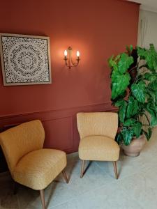 two chairs and a plant in a room at Hôtel-restaurant Les Colonnades in Saint-Fulgent