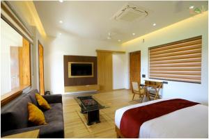 Sahib Farms and Resorts في دلهي: غرفة بسرير واريكة وتلفزيون