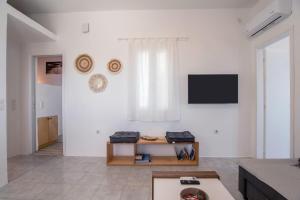 a living room with a tv on a white wall at Punda Beach Seaside Retreat in Logaras